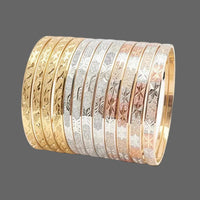 A stack of nine bangles in different metal finishes, including yellow gold, silver, rose gold, and white gold, each featuring an engraved floral pattern on the outer surface, displayed on a clean white background.